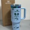Gourde Stanley Flowstate Tumbler 40 oz avec anse — bleu clair avec motifs vert et bande métallique irisée, motif personnage rond assis à grande tête et