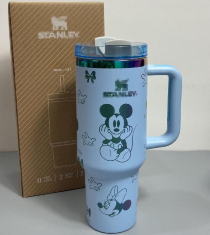 Gourde Stanley Flowstate Tumbler 40 oz avec anse — bleu clair avec motifs vert et bande métallique irisée, motif personnage rond assis à grande tête et