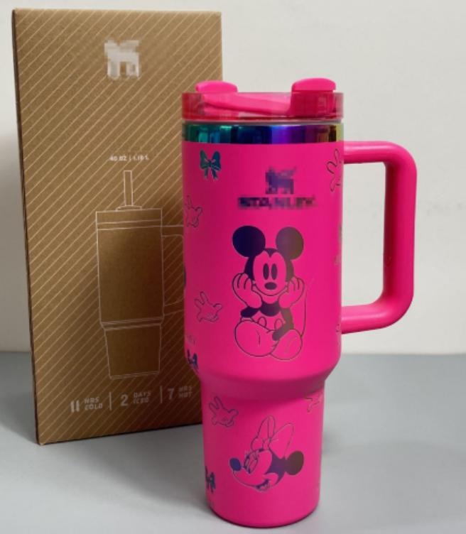 Gourde Stanley Flowstate Tumbler 40 oz avec anse — rose fuchsia avec motifs sombres et bande métallique irisée, motif personnage rond assis à grande tête et