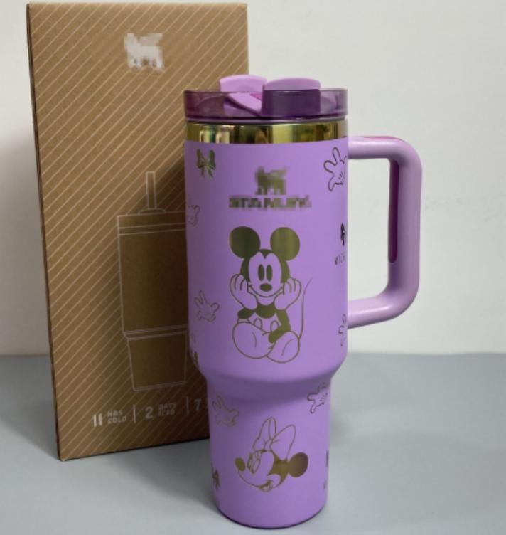 Gourde Stanley Flowstate Tumbler 40 oz avec anse — violet/lilas avec motifs dorés, motif personnage rond assis à grande tête et