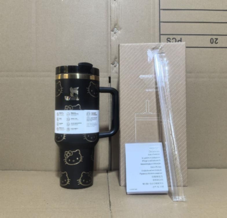 Gourde Stanley Flowstate Tumbler avec anse — noir avec motif doré, finition dorée sur le bord supérieur, motif personnage félin doré stylisé avec noeud