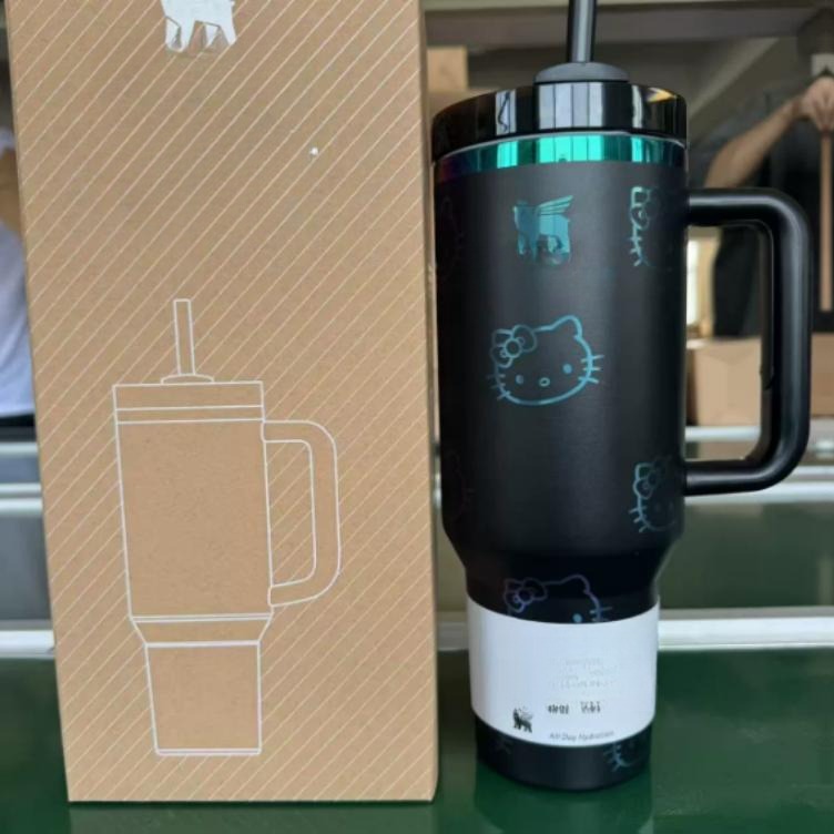 Gourde Stanley Quencher H2.0 Tumbler 40 OZ | 1.18 L avec anse — noir avec motif bleu/turquoise dégradé irisé, motif personnage félin blanc stylisé avec noeud