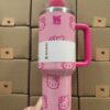 Gourde Stanley Quencher H2.0 Tumbler 40 OZ | 1.18 L avec anse — rose pâle avec motif blanc/rose foncé, motif personnage félin blanc stylisé avec noeud