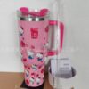 Gourde Stanley Quencher H2.0 Tumbler avec anse — rose avec motifs blanc/rouge, édition Hello Kitty / Sanrio
