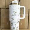 Gourde Stanley Quencher Tumbler vide avec anse — blanc / crème, motif mêmes scènes en contours dorés : chien couché