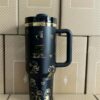 Gourde Stanley Quencher Tumbler vide avec anse — noir, motif multiples scènes en contours dorés :